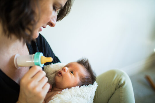 Attentive new mother feeds her newborn baby with bottle