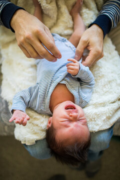 Detail of father dressing his son in blue clothing.