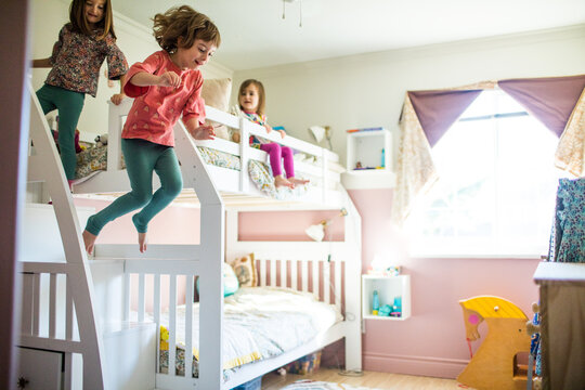 Young girls having fun, playing, jumping off bunk bed in bedroom