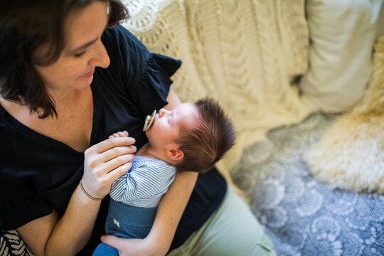 High angle view of mother holding her newborn son at home.