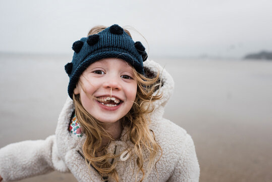 playful portrait of girl playing at the beach on a windy day