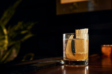 A mostly transparent craft cocktail with a cornhusk garnish.