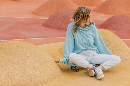 Teenager on skateboard relaxing sitting in skate park.