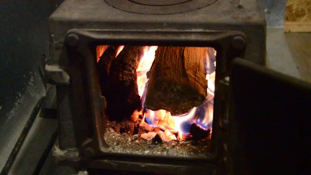 Firewood is burning in the firebox of a cast-iron 