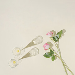 Champagne glasses with pink roses on a pastel beige background. Love concept. Romantic idea.