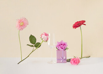 Flowers,  gift and glass on a colorful background. Creative romantic concept. Minimal love idea