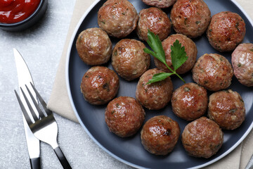 Tasty cooked meatballs with parsley served on light grey table, flat lay