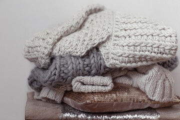 Close up of neatly folded knitted items of pastel color on a light background.