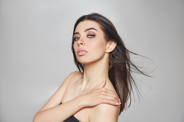 Naklejka premium beautiful makeup on a young girl. studio portrait of a woman with clear skin on a gray background. natural beauty