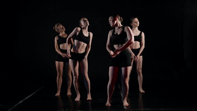 young female dancers are training modern choreography in dark studio, slow motion of dancing women