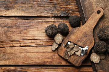 Shaver with whole and sliced black truffles on wooden table, flat lay. Space for text - obrazy, fototapety, plakaty