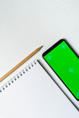White blank notepad smartphone green screen mockup and pencil flat lay. Tamplate for design