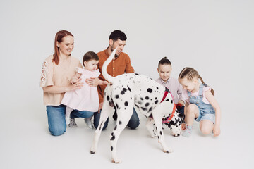 Young Family with kids playing with a dalmatian dog on white background
