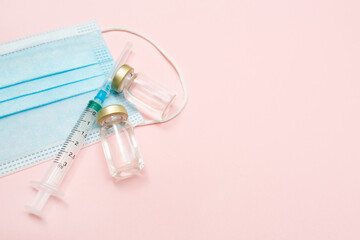 Syringe, covid 19 vaccine and medical mask on a pink background. Keep your health. Vaccination. Medical treatment concept. Flat lay. Immunity. Copy space. Place for text