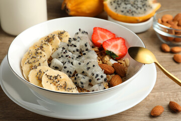 Bowl of granola with pitahaya, banana, almond and strawberry on wooden table, closeup