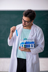 Young male chemist in front of blackboard