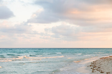 Fototapeta premium Gentle Sunrise on the coast of the Atlantic Ocean. Seascape with turquoise waves of the sea, pink hues on a sunset on a tourist beach. Relaxing holidays by the sea at the magical sunset of Varadero