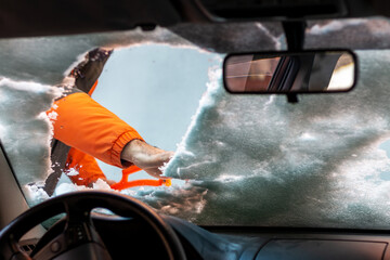Man  cleaning car windshield with scraper from snow and ice