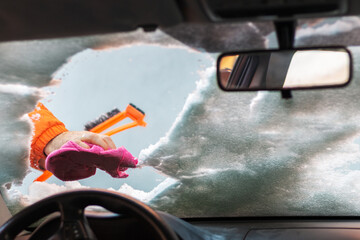 Man  cleaning car windshield with scraper from snow and ice. 
Windshield wiper cloth.