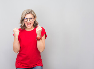 Attractive middle aged woman very happy and excited doing winner gesture with arms raised, smiling and screaming for success. Winner and celebration concept.