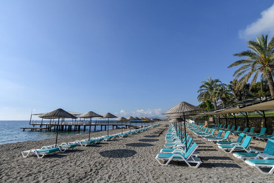 Lounge beach chairs and straw umbrellas near the sea shore.