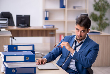 Young businessman employee unhappy with excessive work in the of