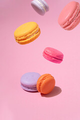 Multicolored macaron almond cakes take off on a pink background