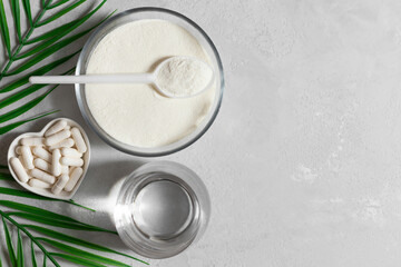 Collagen powder and pills on a gray background with green palm leaves. Healthy supplements concept. Copy space, top view, flat lay.