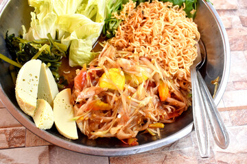 Spicy papaya salad or Thai called SomTum, side dish with mixed vegetables,  egg and instant noodles. Yummy easy cooked at home.