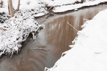 small stream in the snowy forest.and snow covered trees. Winter nature.