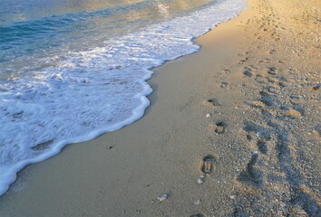 Steps in the sand by the foamy sea