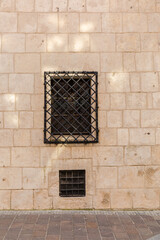 Building wall with a window and wrought iron bars.