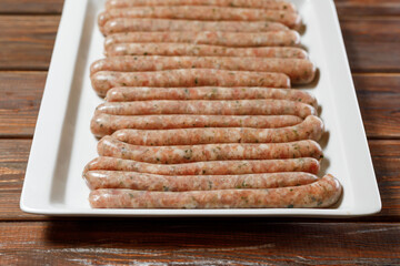The chef is preparing a plate of long sausages to be fried.