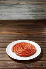 On the background there is a white plate of long sausage.