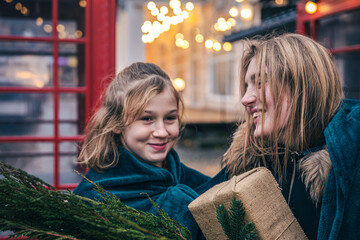 A little girl and young woman with thuja branches and a gift under a plaid.