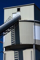 Industriegebäude Turm eckig und Silo zylindrisch Förderstation Lager grau mit Transportrohr