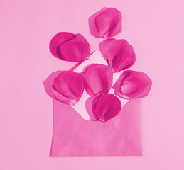 Rose petals getting out of a pink envelope on a pastel pink background. Minimalist concept. Events and anniversaries. Floral pattern. Monochromatic style. Copy paste. Flat lay.