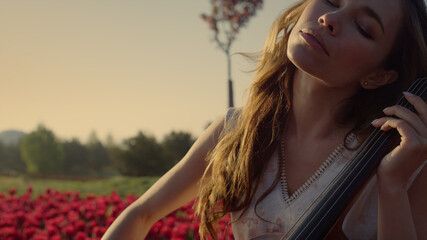 Inspired woman with cello making solo concert in beautiful spring park outdoors. © stockbusters