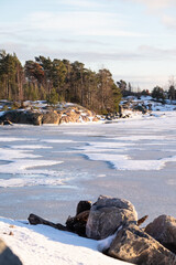 A view of a small island across a frozen river during a sunny winter day.