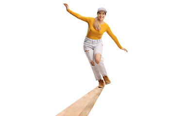 Beautiful trendy young female trying to balance on a wooden beam