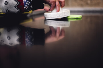 Selective focus on an air hockey table and a small child holding the paddle. 