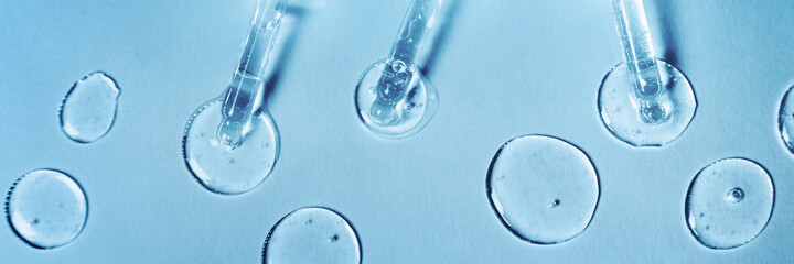 Banner made with transparent gel or serum pipettes with drops on blue background. Cosmetics or...