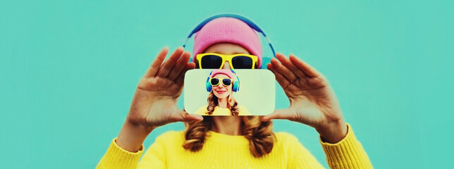 Close up of woman stretching her hands taking selfie picture by smartphone in headphones listening to music on blue background - Powered by Adobe