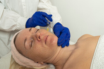 Needle mesotherapy in a beauty clinic. Cosmetics are injected into the woman's face