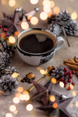 Black coffee mug decorated with pine cones berries and cinnamon sticks