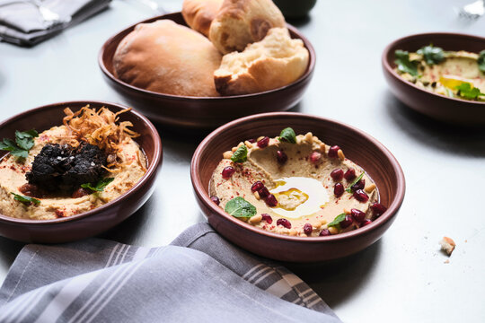 Various types of gourmet hummus on a full table with bread.