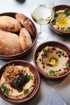 Various types of gourmet hummus on a full table with bread.