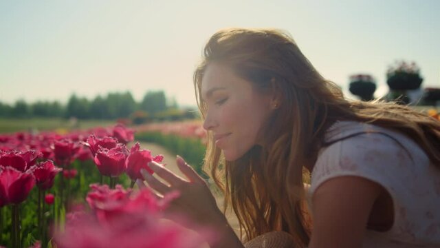 Emotional girl smelling flowers in sunset light. Beautiful woman enjoying flower