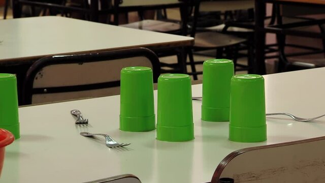 Plastic Cups and Metal Forks on Empty Table at a Public School Canteen in Buenos Aires, Argentina. Close Up.
