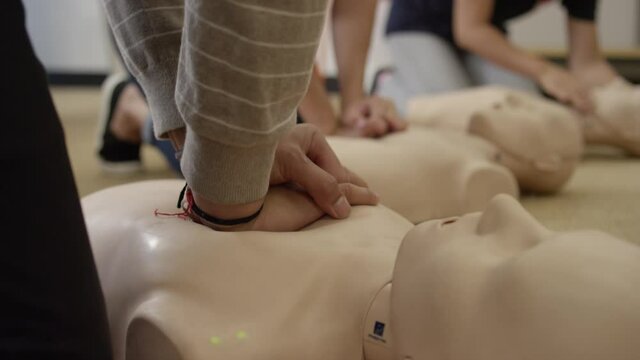 Close up practicing chest compression on dummy in EMT first aid training